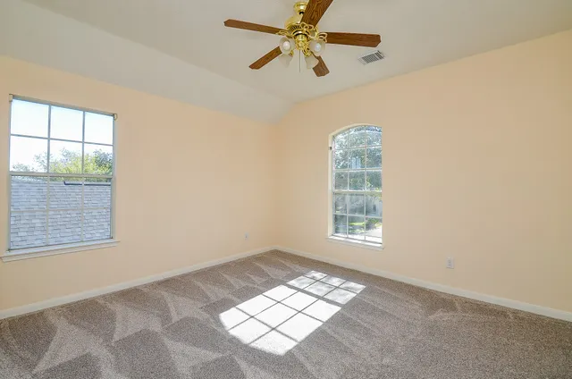 an empty room with windows and fan