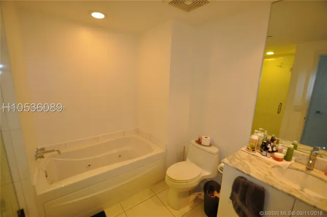 a bathroom with a granite countertop bathtub sink vanity mirror and toilet