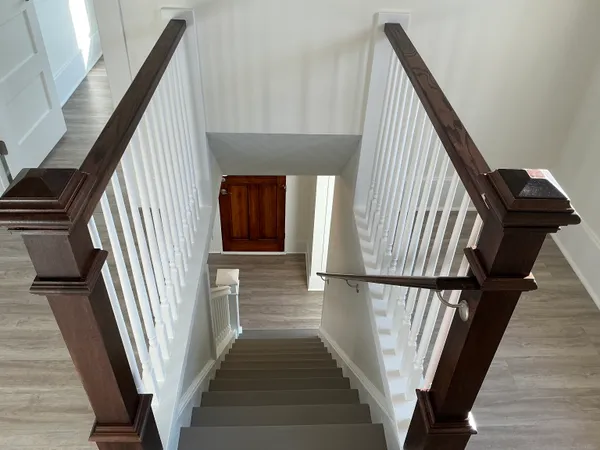 a view of staircase with lots of frames on wall and wooden floor