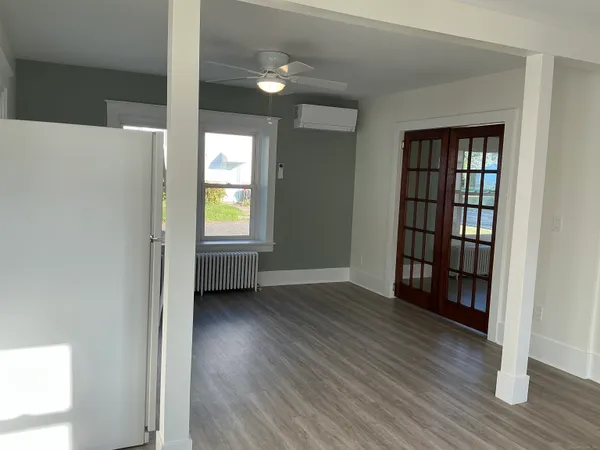 a view of an empty room with wooden floor and a window