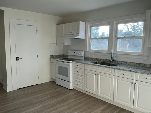 a kitchen with granite countertop white cabinets and a sink