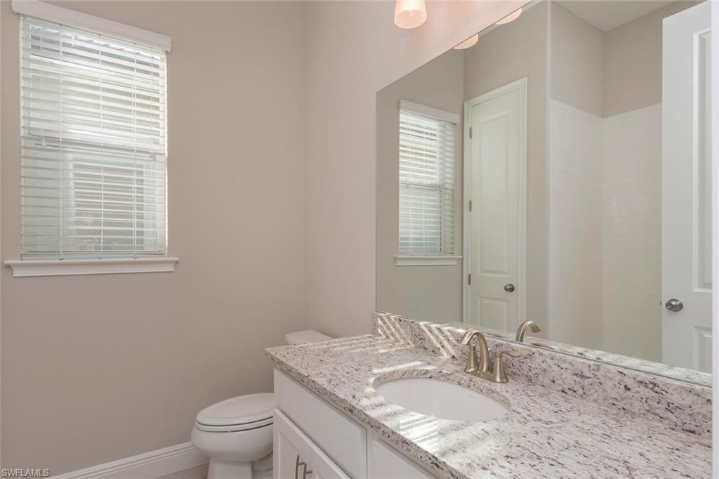 3331 Pilot Circle Naples, FL 34120 - Photo 17 of 28 a bathroom with a granite countertop sink toilet a mirror and a window