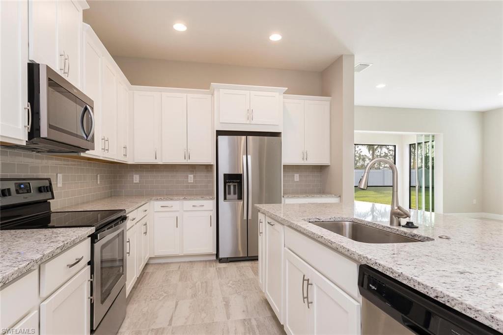 3331 Pilot Circle Naples, FL 34120 - Photo 8 of 28 a kitchen with granite countertop a sink stainless steel appliances and white cabinets