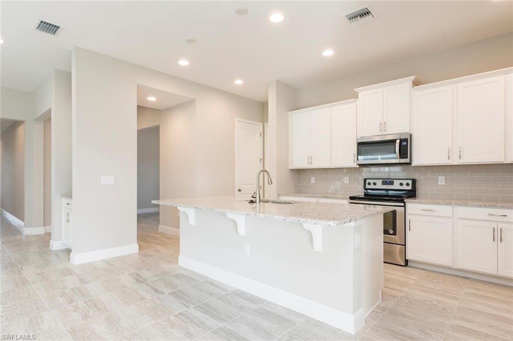 3331 Pilot Circle Naples, FL 34120 - Photo 9 of 28 a large kitchen with stainless steel appliances granite countertop a stove a sink and a microwave