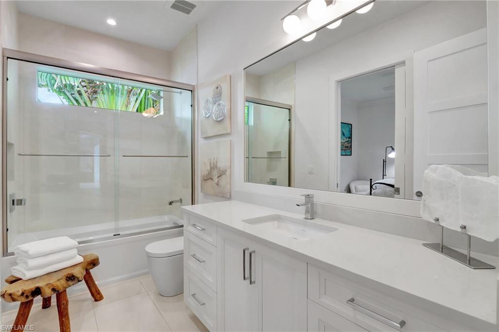 2120 Curtis Street Naples, FL 34112 - Photo 17 of 38 a bathroom with a granite countertop sink a toilet a mirror and shower
