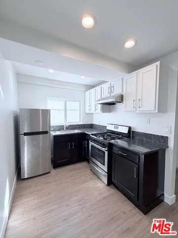 a kitchen with stainless steel appliances granite countertop a stove a refrigerator and a sink with wooden floors