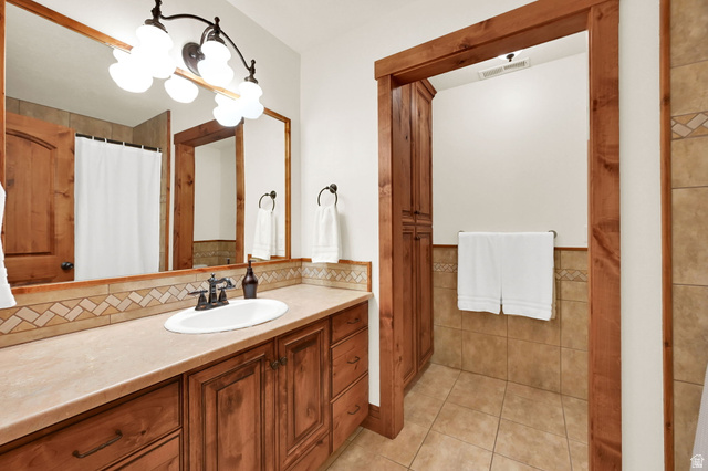 13658 South Fort Street Draper, UT 84020 - Photo 28 of 87 Bathroom featuring a single basin vanity with extensive wood cabinetry, a light-toned countertop, and a decorative tile backsplash