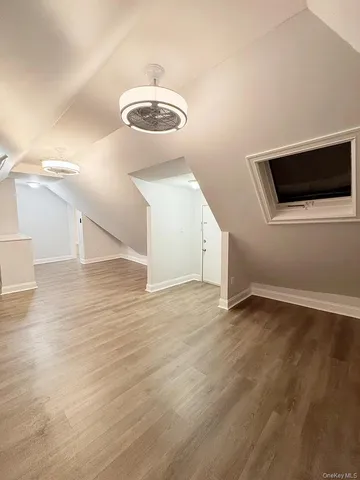 a view of an empty room with wooden floor and chandelier