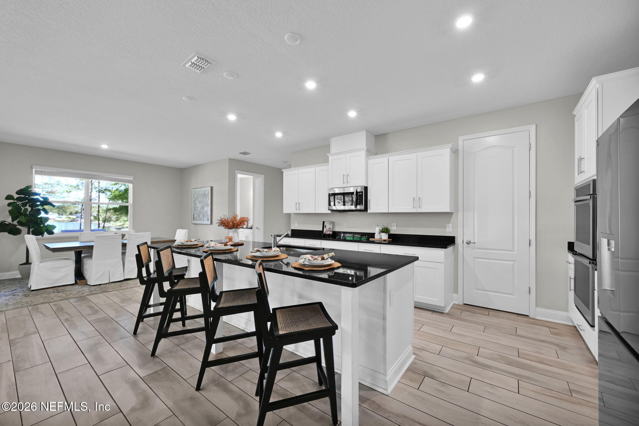 4050 Coyote Court Middleburg, FL 32068 - Photo 17 of 93 a kitchen with stainless steel appliances kitchen island granite countertop a stove a sink a refrigerator and white cabinets with wooden floor