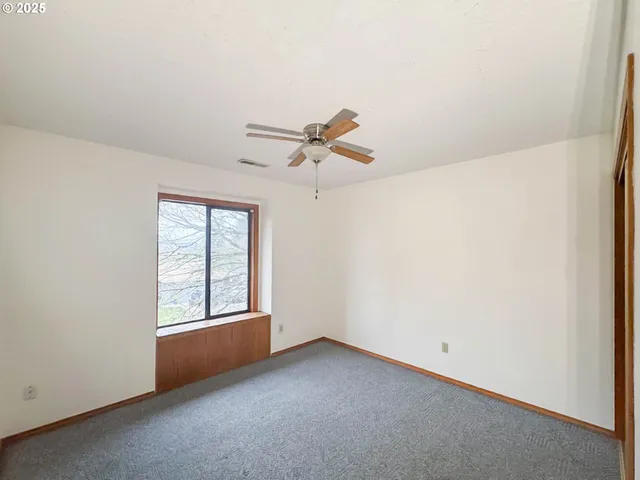an empty room with ceiling fan and windows