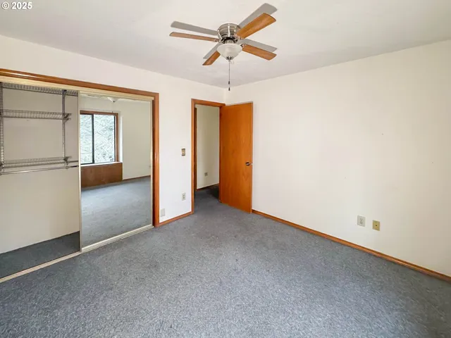 an empty room with chandelier fan and windows
