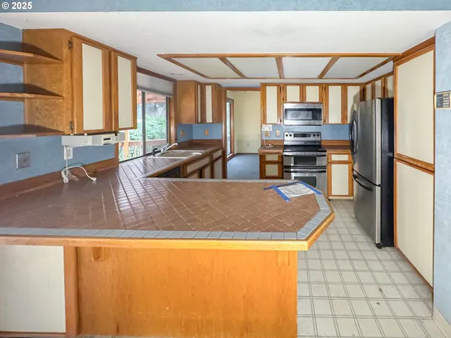 a view of a kitchen with kitchen island a counter top space a sink a refrigerator and a lots of counter space