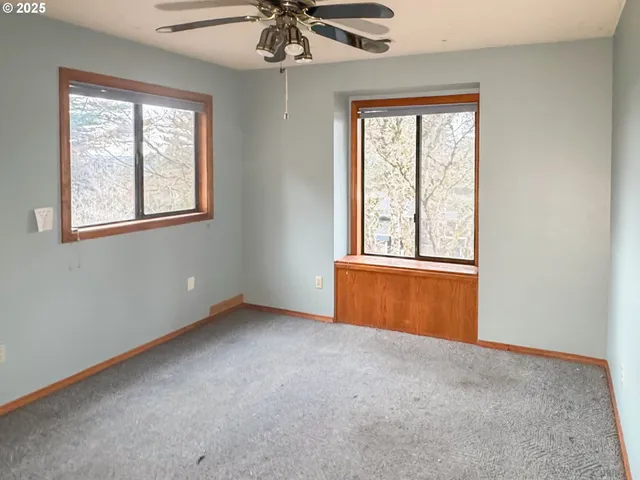 an empty room with windows and fan