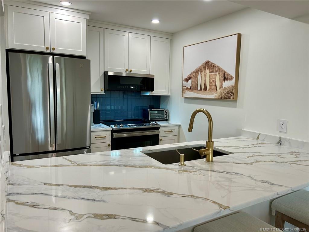 484 Northeast Plantation Road, Unit 4102 Stuart, FL 34996 - Photo 11 of 35 a kitchen with stainless steel appliances kitchen island a refrigerator sink and cabinets
