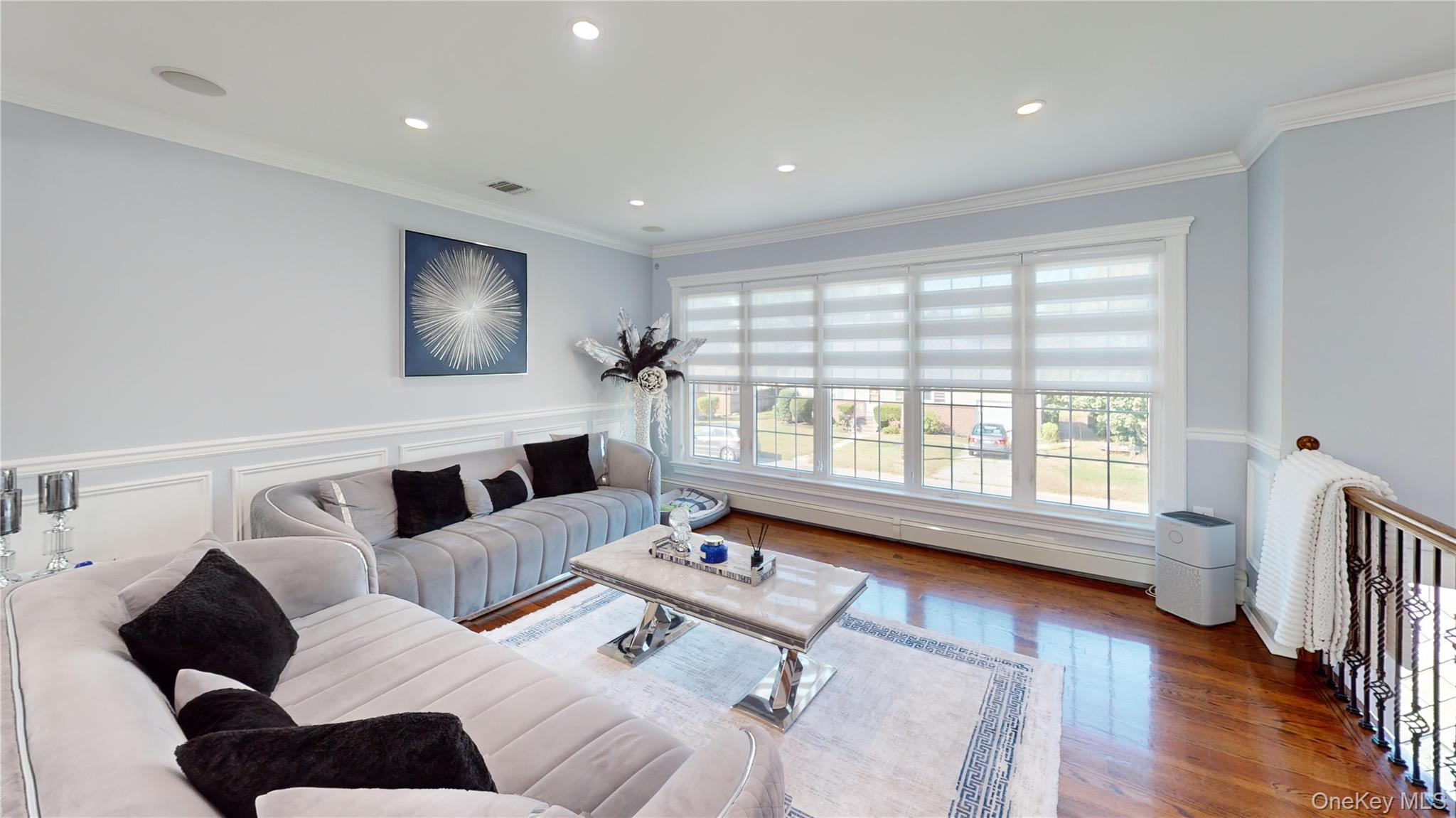 125 Spruce Street Lindenhurst, NY 11757 - Photo 11 of 29 Living room with plenty of natural light, ornamental molding, wood finished floors, recessed lighting, and a wainscoted wall