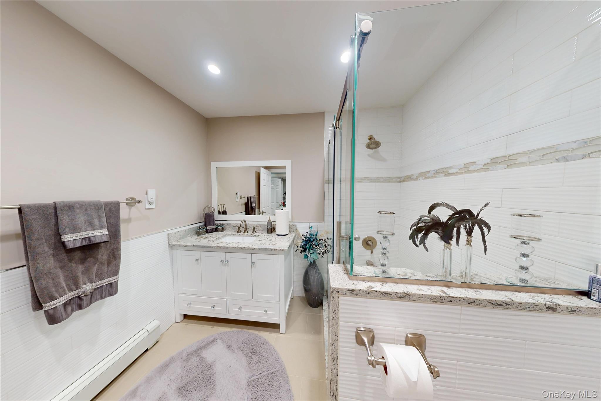 125 Spruce Street Lindenhurst, NY 11757 - Photo 17 of 29 Full bath featuring a wainscoted wall, a baseboard radiator, walk in shower, vanity, and tile walls