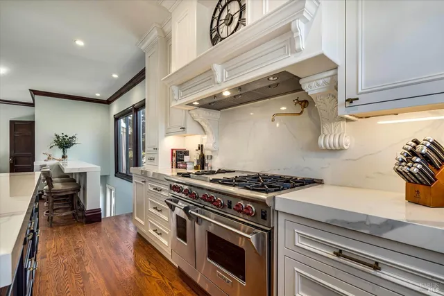 a kitchen with stainless steel appliances granite countertop a stove a sink and a wooden floors
