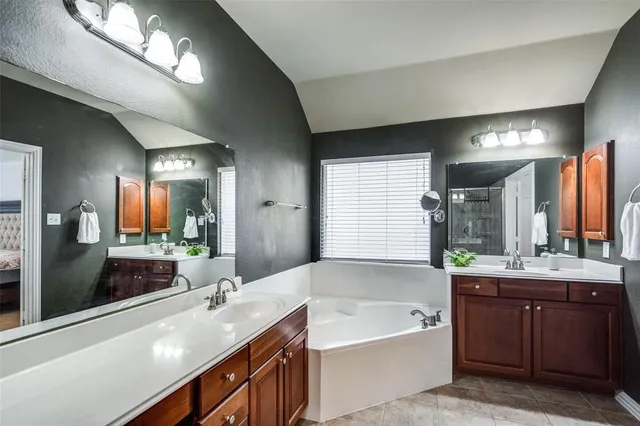 a bathroom with a bathtub a double vanity sink and a large mirror