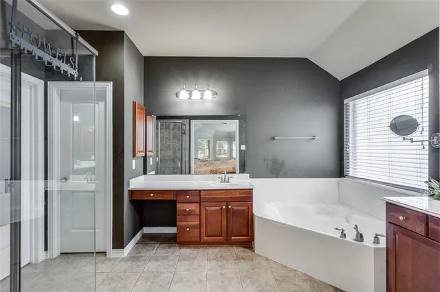 a bathroom with a tub a sink and a large mirror