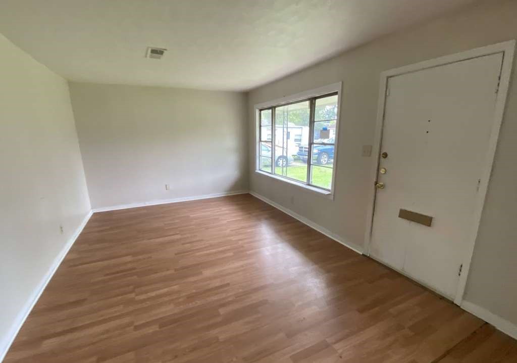 5715 Belmark Street Houston, TX 77033 - Photo 4 of 13 an empty room with wooden floor and windows