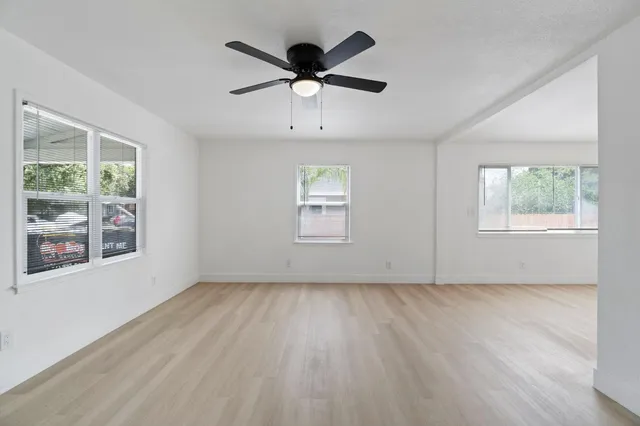 a view of an empty room with wooden floor and a window
