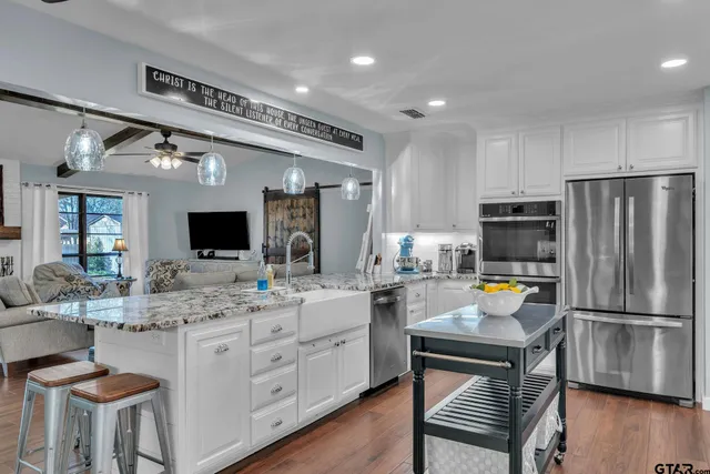 a kitchen with a refrigerator a sink dishwasher a stove and a dining table with wooden floor