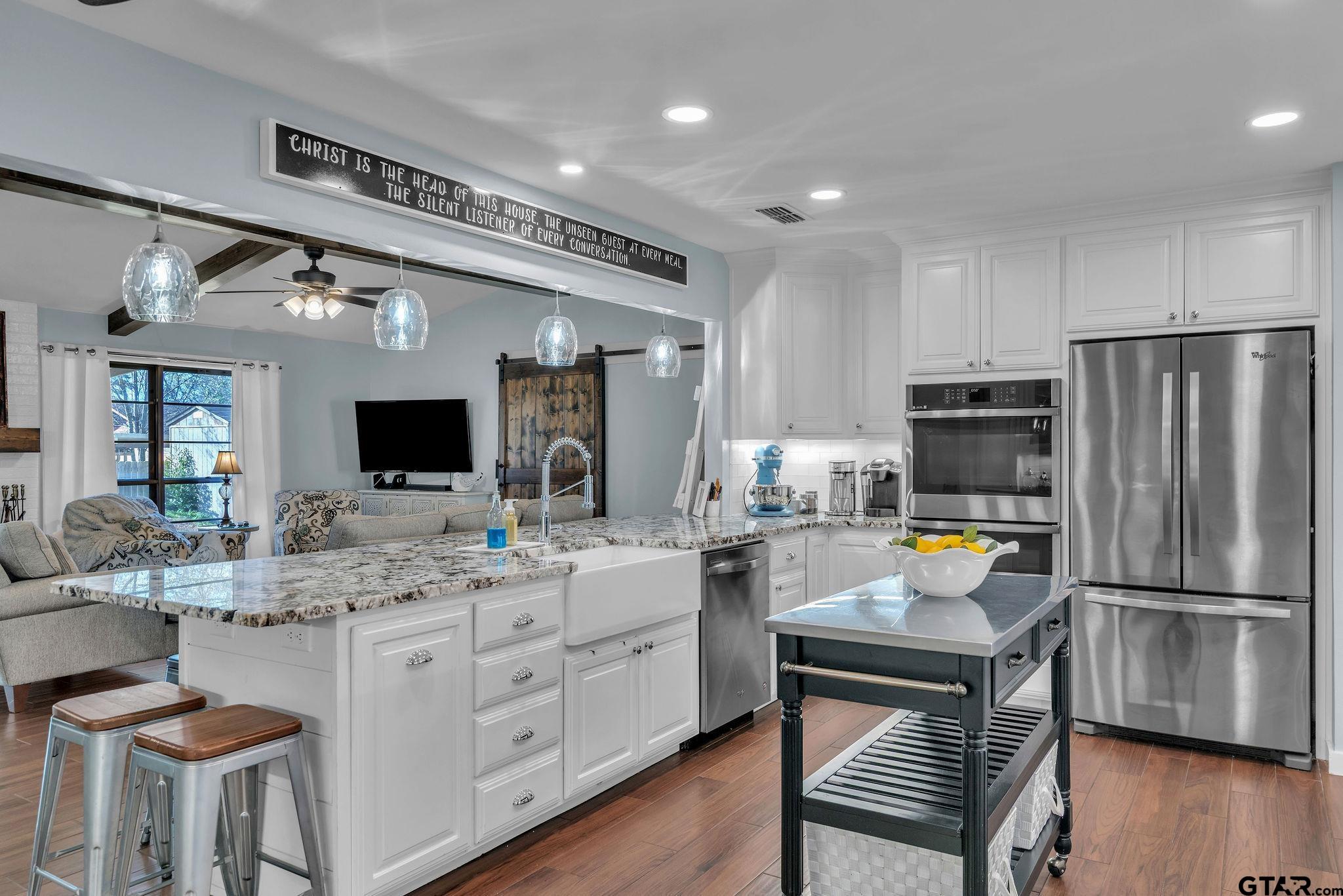 1208 Briarwood Lane Longview, TX 75604 - Photo 12 of 43 a kitchen with a refrigerator a sink dishwasher a stove and a dining table with wooden floor