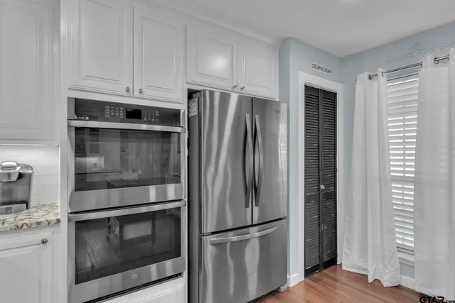 a metallic refrigerator freezer sitting inside of a kitchen
