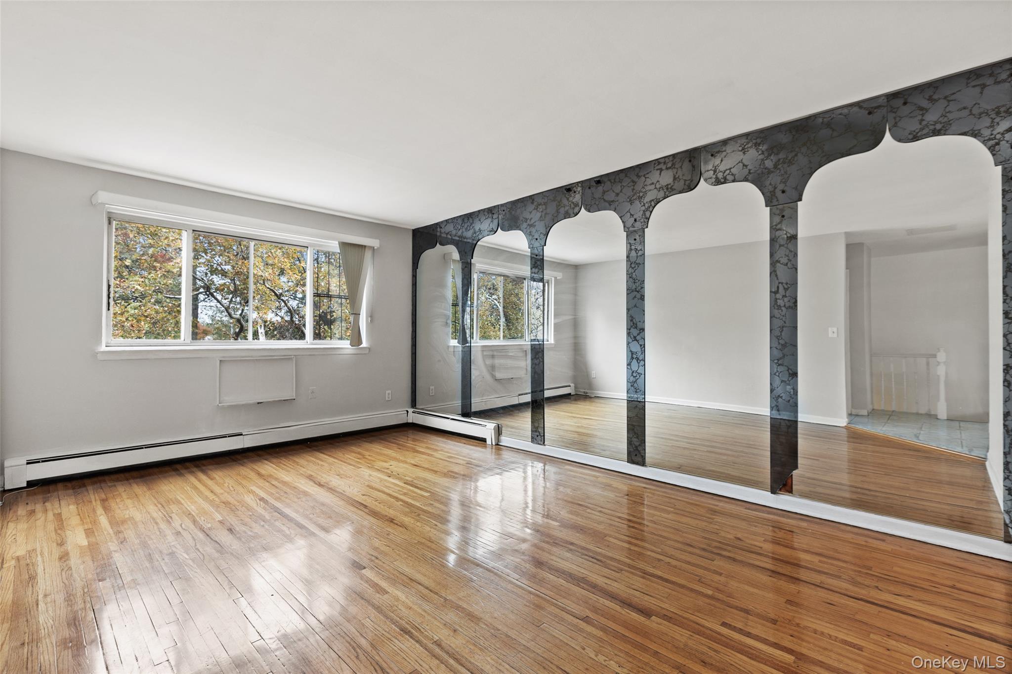a view of an empty room with wooden floor and a window