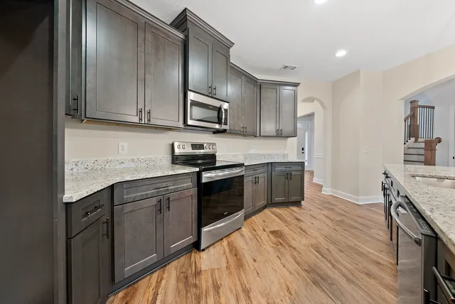 a kitchen with stainless steel appliances granite countertop wooden cabinets a stove top oven a sink and dishwasher