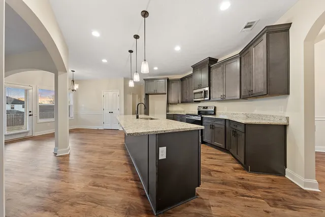 a kitchen with kitchen island granite countertop wooden floors and a sink