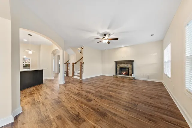 a view of an empty room with wooden floor fireplace and a window