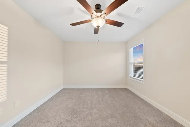 an empty room with a window and a fan