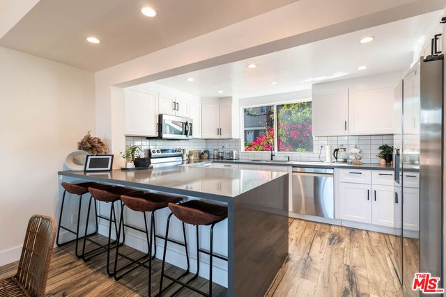 a kitchen with stainless steel appliances granite countertop a sink a stove a refrigerator cabinets and dining table