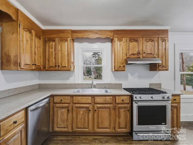 a kitchen with stainless steel appliances granite countertop a stove a sink and a microwave