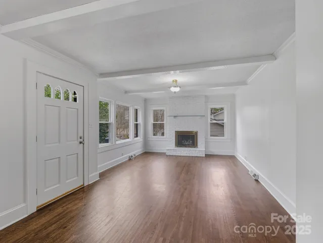 an empty room with wooden floor fireplace and windows