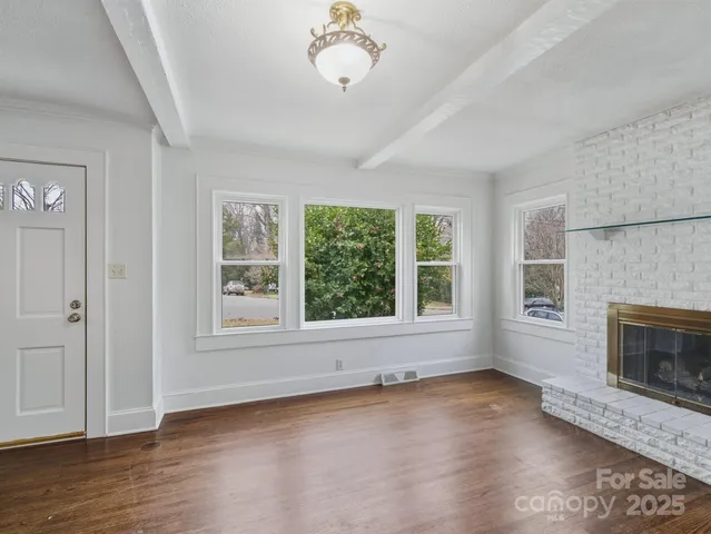 an empty room with wooden floor fireplace and windows