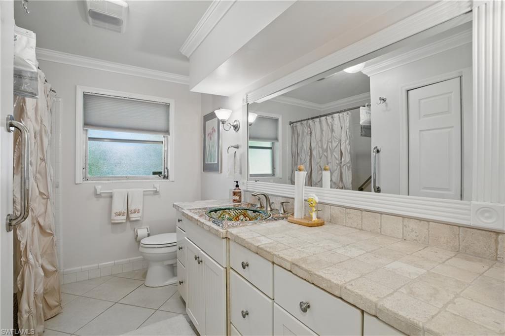 261 Viking Way Naples, FL 34110 - Photo 26 of 40 a bathroom with a granite countertop sink a toilet a mirror and bathtub