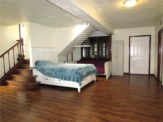 a bedroom with a bed and a night stand with wooden floor