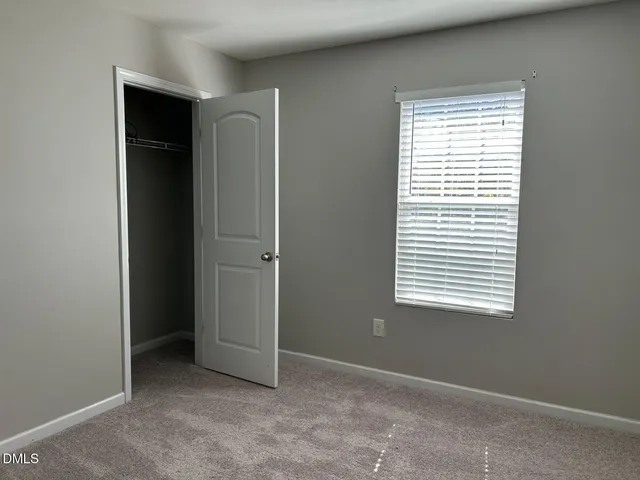 a view of an empty room with closet and a window
