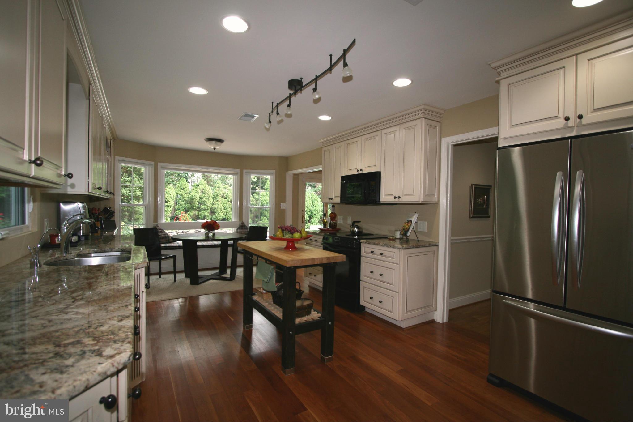 11939 Riders Lane Reston, VA 20191 - Photo 1 of 30 a kitchen with a refrigerator a stove top oven a sink dishwasher a dining table and chairs with wooden floor