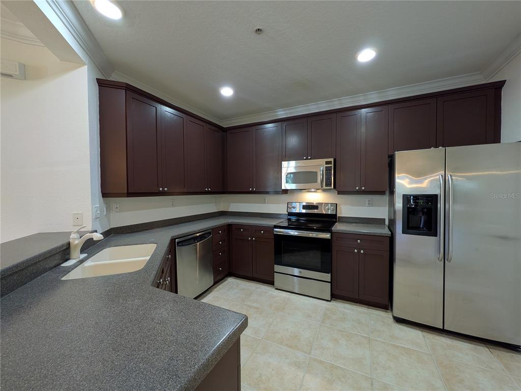 11562 Amidship Lane, Unit 208 Windermere, FL 34786 - Photo 8 of 31 a kitchen with granite countertop a refrigerator and a stove top oven