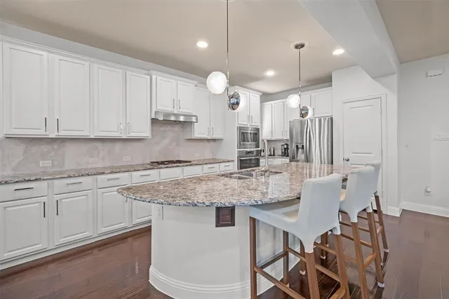 a kitchen with stainless steel appliances granite countertop a white cabinets sink and stove