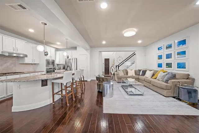 a living room with furniture kitchen view and a wooden floor