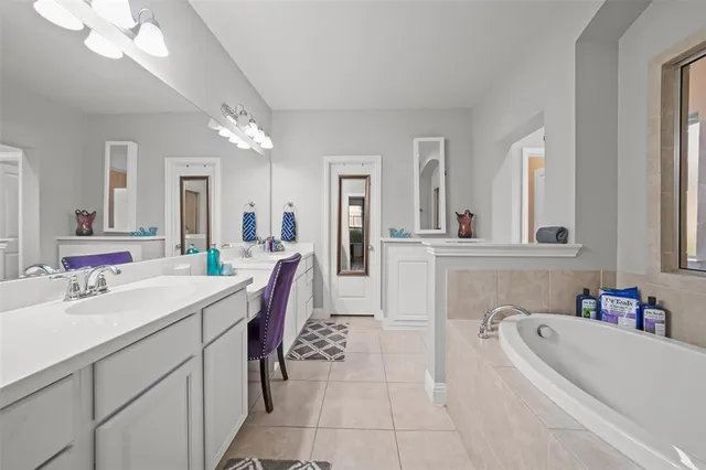 a bathroom with a sink a vanity a mirror and a bathtub
