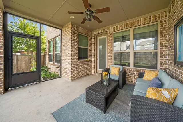 a living room with furniture floor to ceiling windows and ceiling fan
