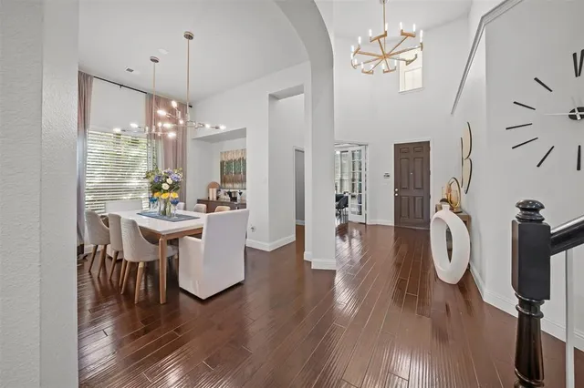 a dining room with wooden floor a chandelier a wooden table and chairs