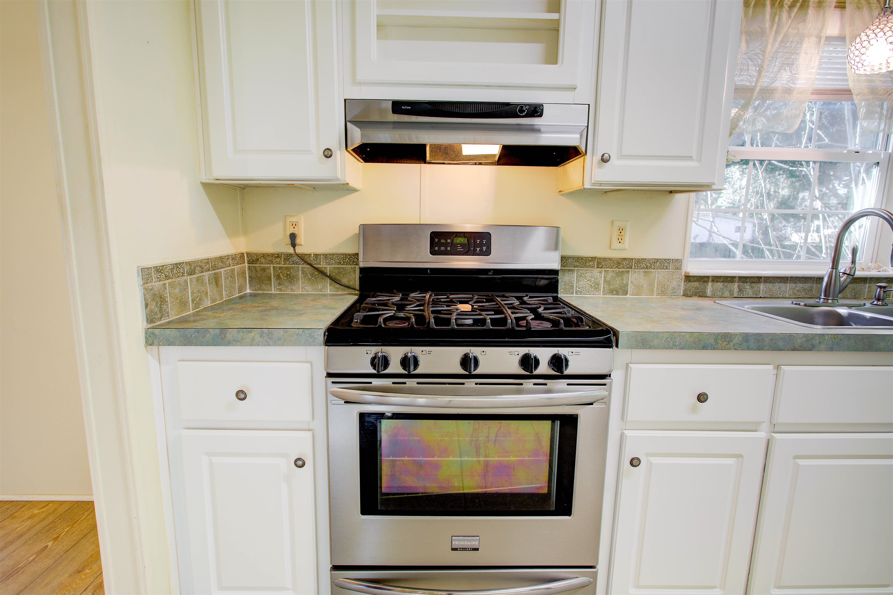 501 Hayley Road St. Augustine, FL 32086 - Photo 17 of 49 Kitchen featuring stainless steel range with gas stovetop, white cabinets, exhaust hood, light countertops, and wood finished floors