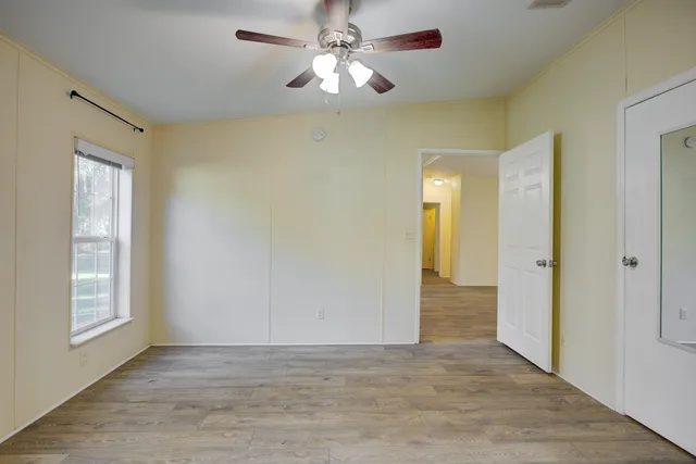 a view of empty room with wooden floor and fan