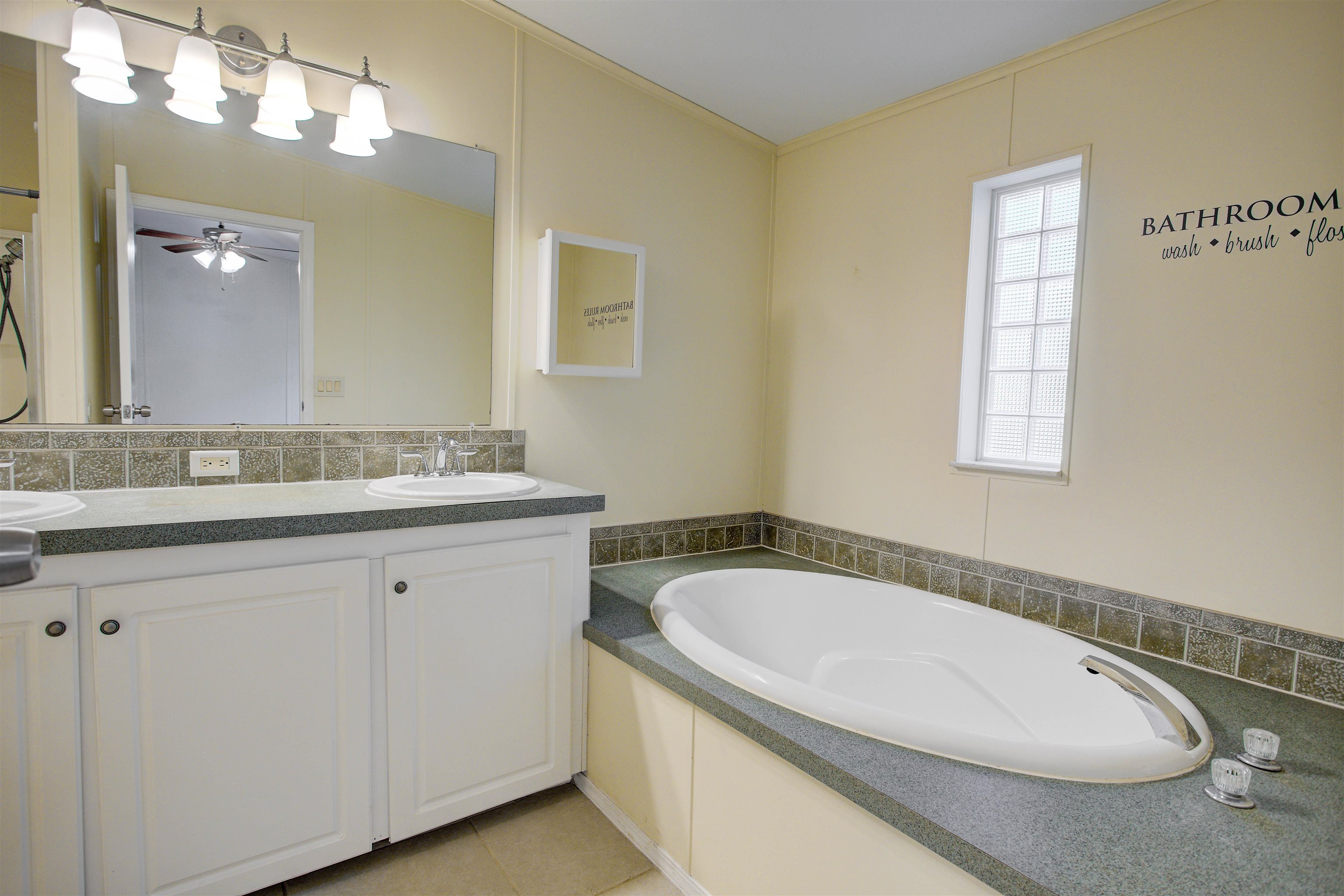 501 Hayley Road St. Augustine, FL 32086 - Photo 23 of 49 Bathroom with double vanity, a bath, decorative backsplash, and light tile patterned floors